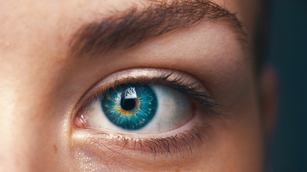 This is a close-up of a Caucasian woman's left eye. There is no obvious makeup. The eye is a rich blue with a ring of gold around the pupil. This represents the sensory stimuli discussed in research on autism and sex.